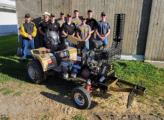 Torq 'n Tigers members pose behind their team's tractor.