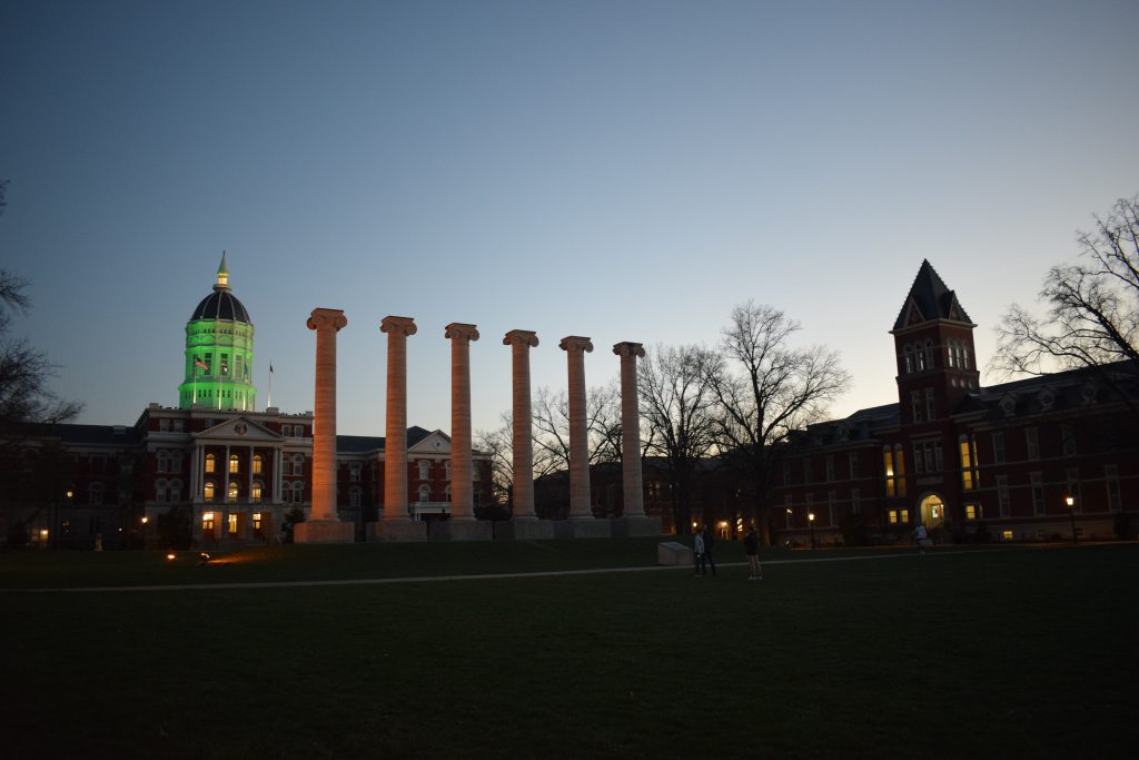 Jesse Hall with the dome lit in green, and Lafferre Hall on the other side of the quad.
