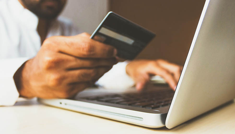 Hand holding credit card at laptop.