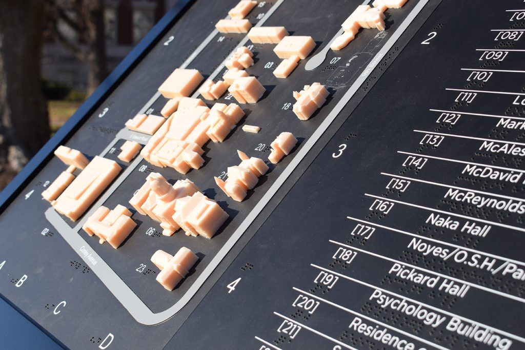 A close-up shot of the tactile map, consisting of small 3D-printed models of various buildings on campus, paired with a Braille legend.