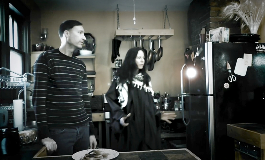 A screencap of Chip Gubera's film, depicting a man and a woman standing together in a kitchen.