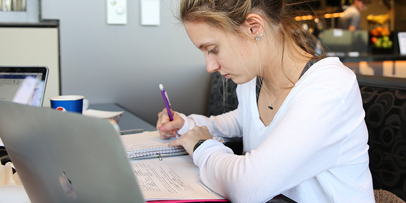 A female student takes notes from a laptop.