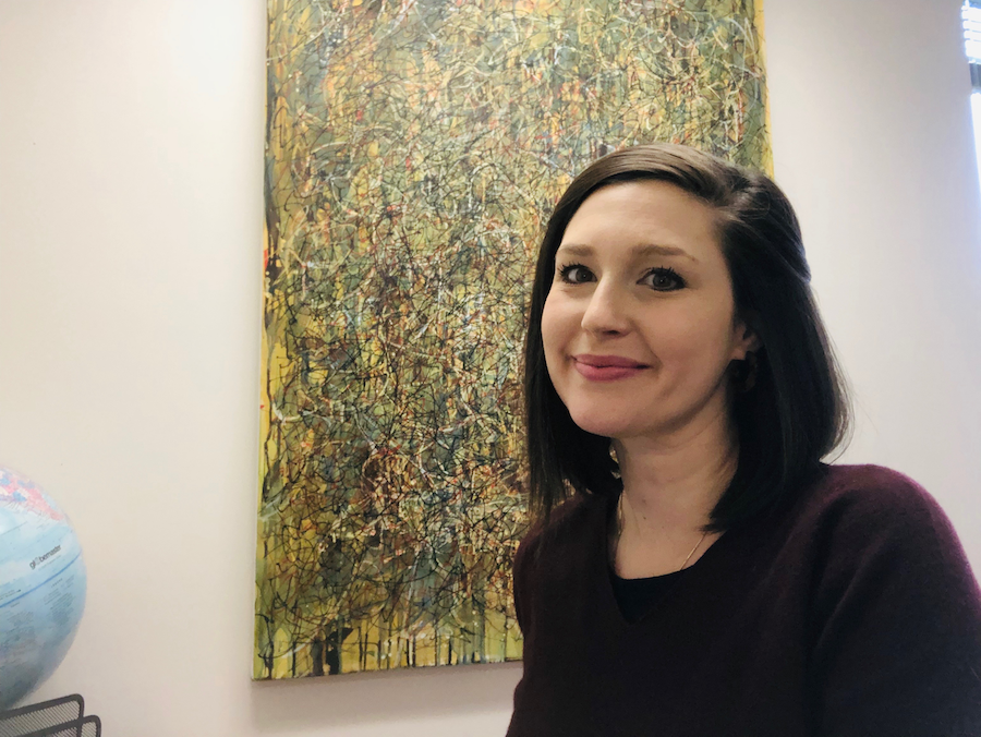 Cassandra Siela smiles in front of an abstract yellow and green painting.