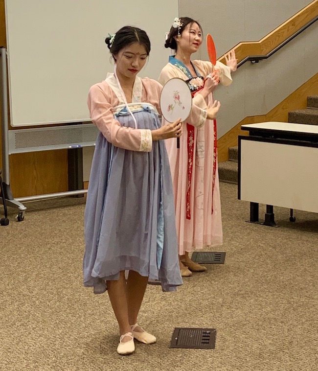 Two young Chinese women perform a round fan dance.