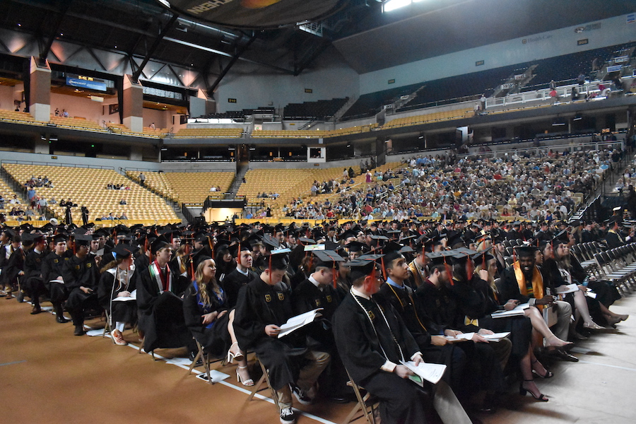 Students wait eagerly in caps and gowns.