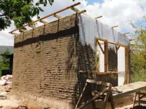 A house in progress, with exposed ceiling beams and mud walls.