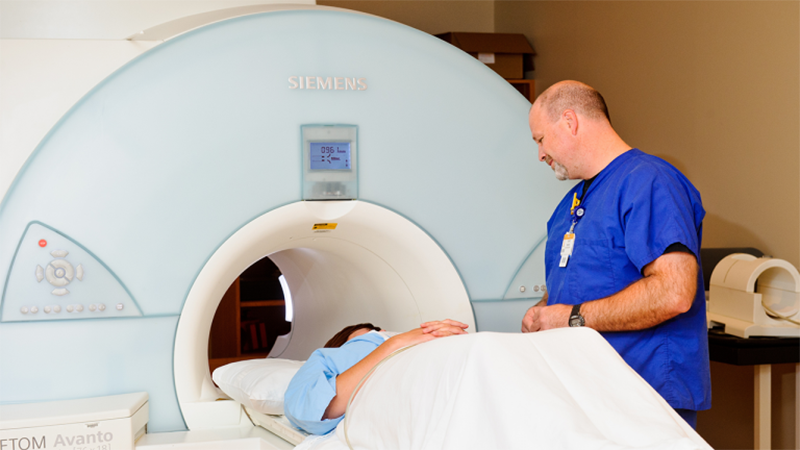 Clinical engineering worker talking with a patient in an MRI machine