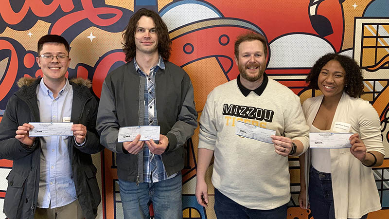 Four people holding checks