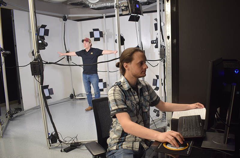 Man at computer with another man inside motion capture system