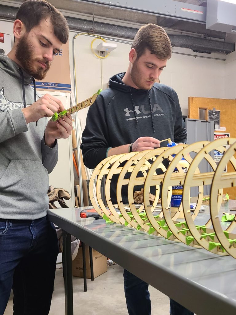 Graham Bond (left) and Joe Jenner (right) using masking tape to hold wood together temporarily so that glue could be applied.