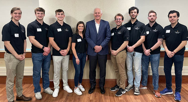 Group of students posed with alumnus