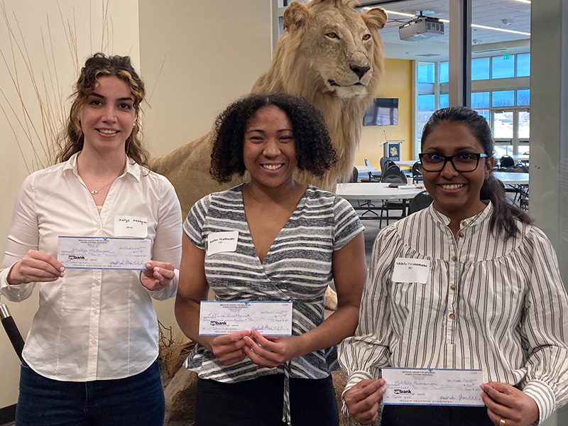 Three students holding prize checks