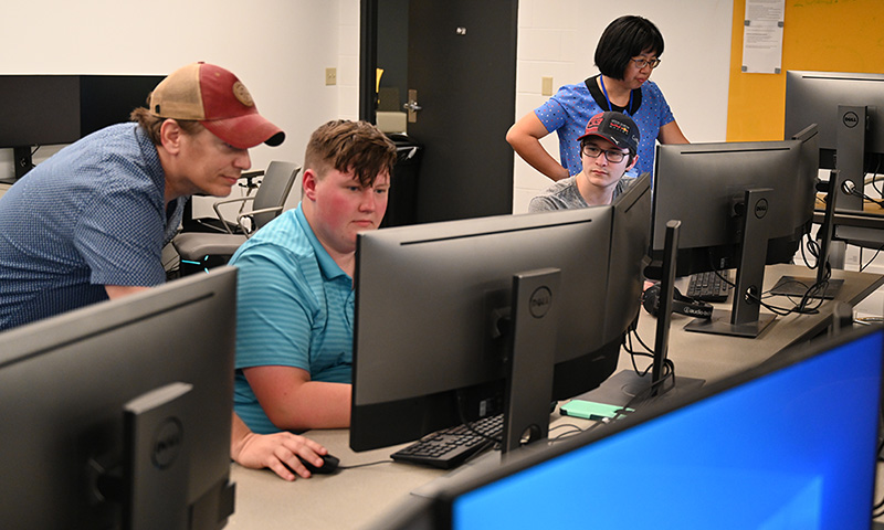 Faculty working with students at computers.