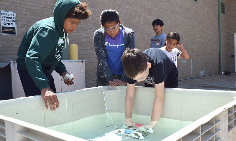 Students test robot in pool of water.