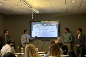 Students presenting to Industrial Engineering faculty and IAB Members. From left, RJ Morrison, Jack Christian, Michael Talarico and Brennan Kiger; project outcomes slide