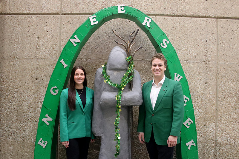 Madi Robinson and Jimmy Keating with the concrete St. Patrick Statue and Engineers' Week arch