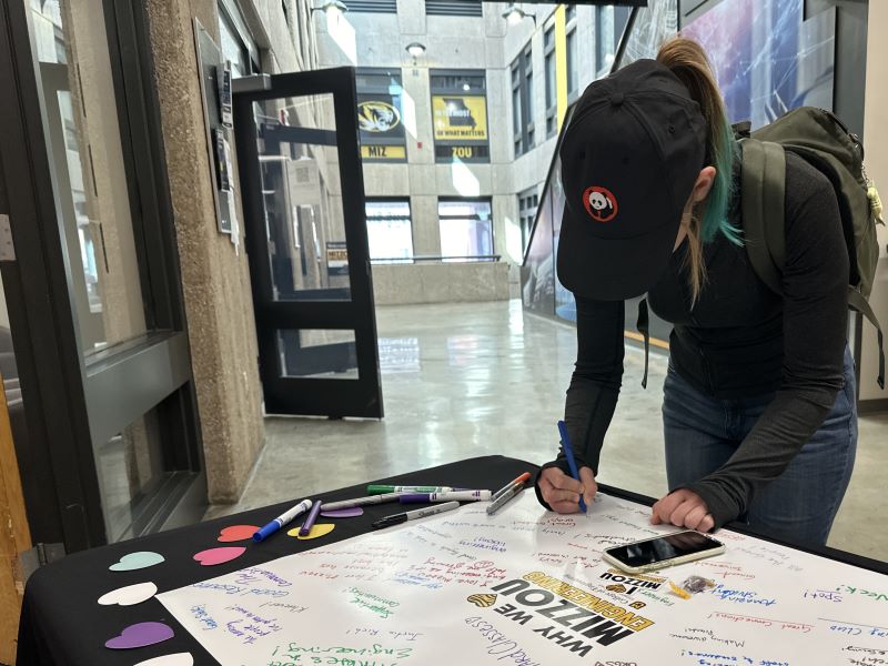 Student writing why they love Mizzou Engineering on poster