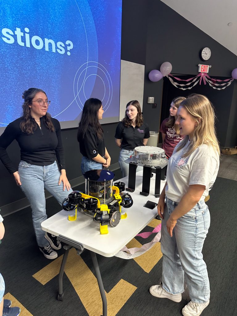 Students' Underwater Robotics Foundation members with robot speaking to girls
