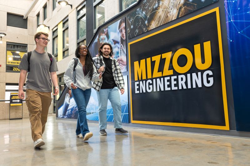 Three students walking in front of Mizzou Engineering wall