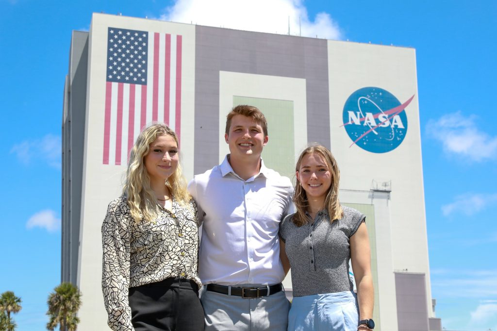 Mizzou Volleyball’s Marina Crownover, Mizzou Football’s Jack Meyer and Mizzou Soccer’s Leah Selm stand in front of the Vehicle Assembly Building at NASA’s John F. Kennedy Space Center in Florida during their micro-internship.