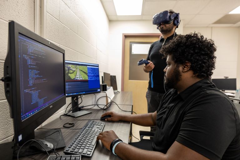 Two graduate students test VR technology in Khaza Anuarul Hoque's lab.