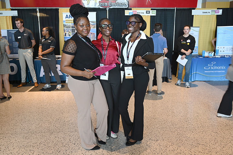 Three students posed, smiling at career fair