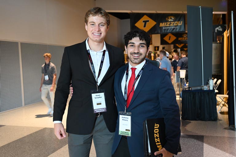 Two students posed, smiling at career fair