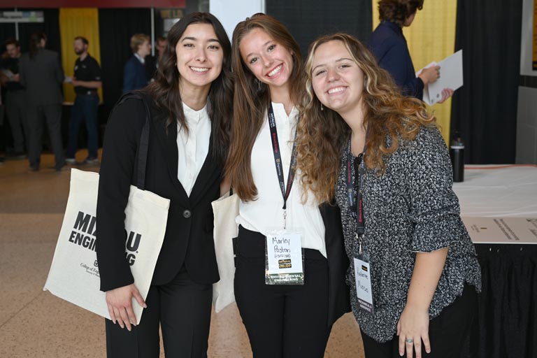 Three students posed, smiling at career fair