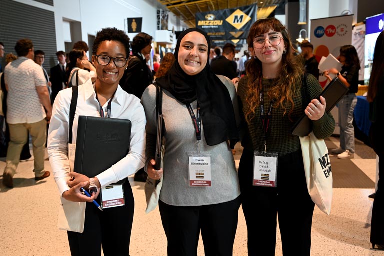 Three students posed, smiling at career fair