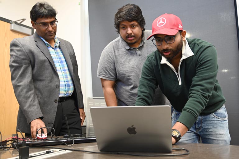 Students and Calyam working on computer