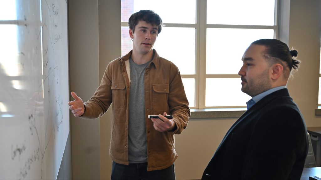 Benjamin Peter and Mert Korkali discuss research on whiteboard