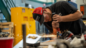 Member of Mizzou Quarter Scale Tractor Pulling Team uses grinder in workshop