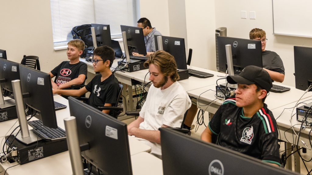 Two rows of five young men seated at desktop computers