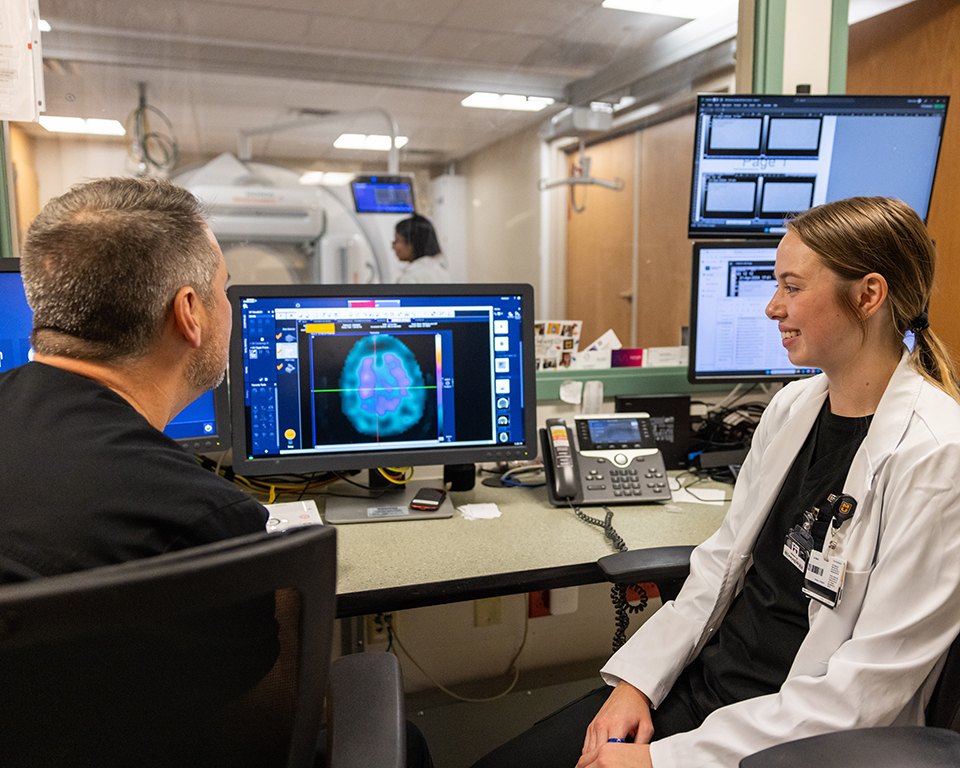 Two people looking at a computer screen with neuro imaging