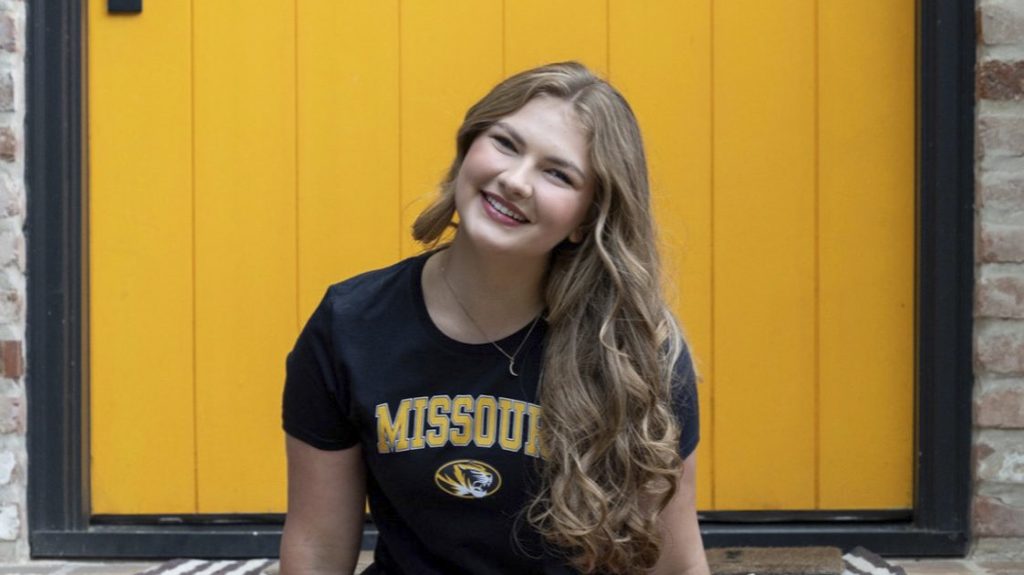 Olivia Esbeck in black and gold Missouri T-shirt against yellow backdrop