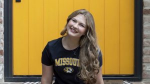 Olivia Esbeck in black and gold Missouri T-shirt against yellow backdrop