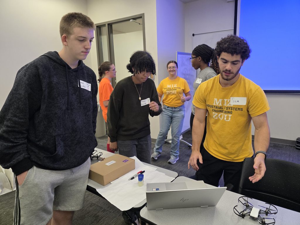 Camp participants and volunteers observe the screen of a laptop computer.