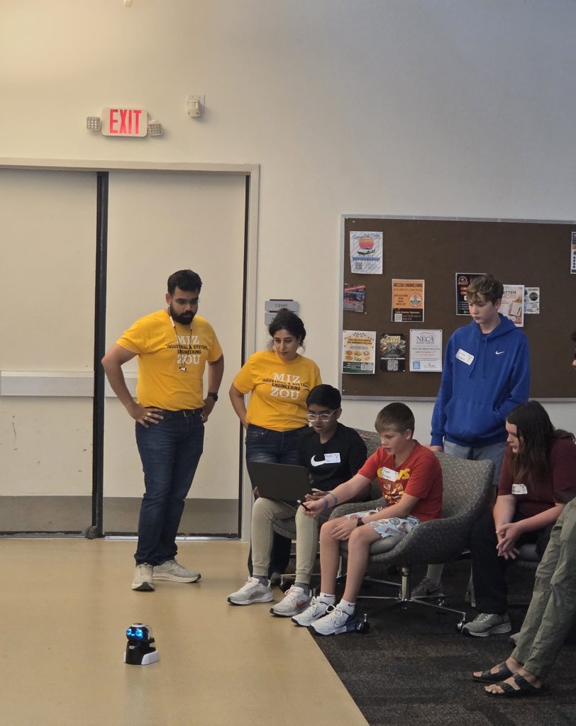 Camp volunteers demonstrate a small robot for campers