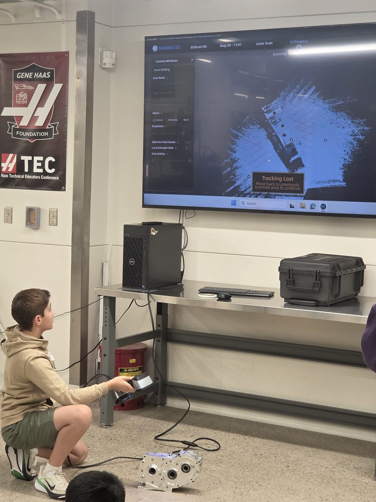 A student explores advanced manufacturing technology through a hands-on 3D scanning activity, creating a digital representation of a physical component.