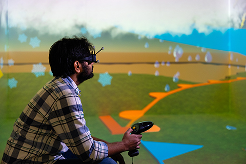 Man with a VR head set sits in the CAVE