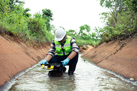 Environmental engineer tests water in a creek