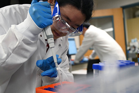 Woman uses a pipette in a lab